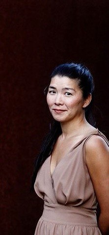 Portrait of jeanie wearing a rose-colored dress against a dark background